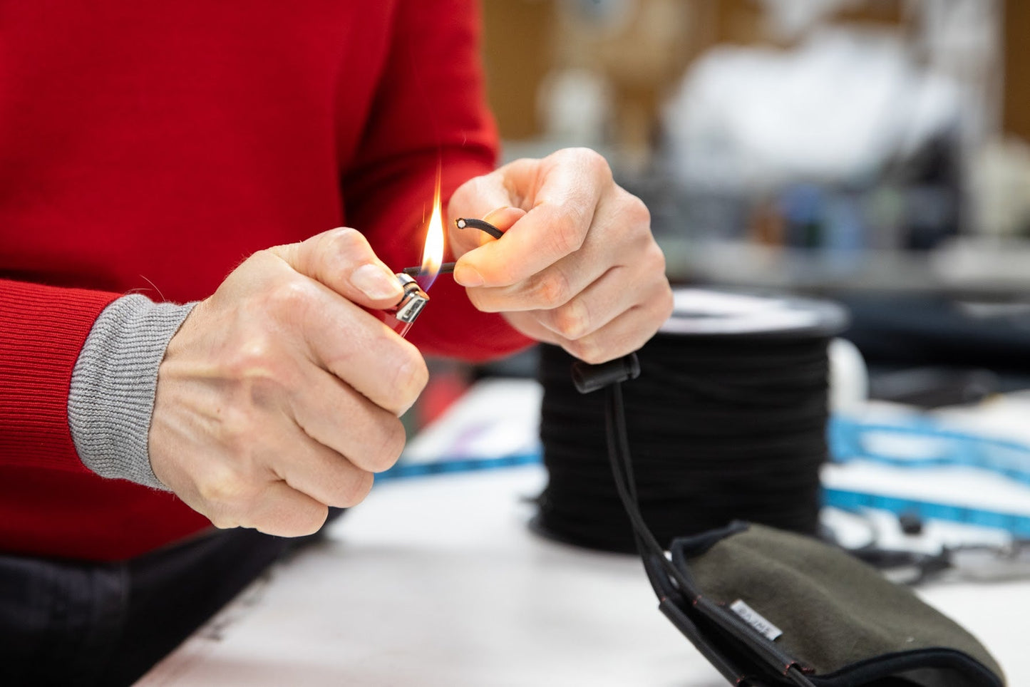 muriel using a lighter to seal the ends of the elastic cord for the 3 layer felted wool mask