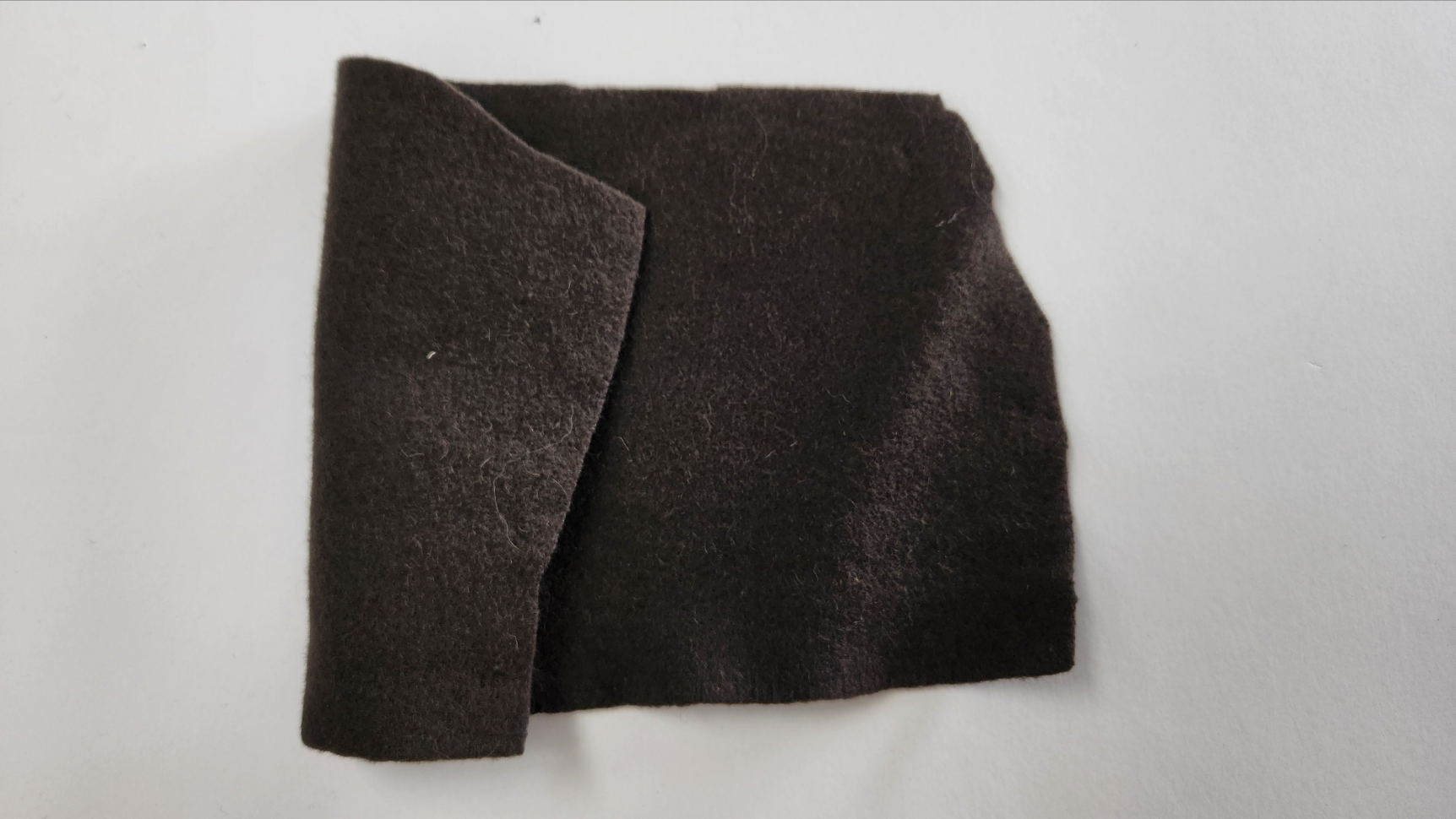 Dark olive wool felt fabric sample on a white background