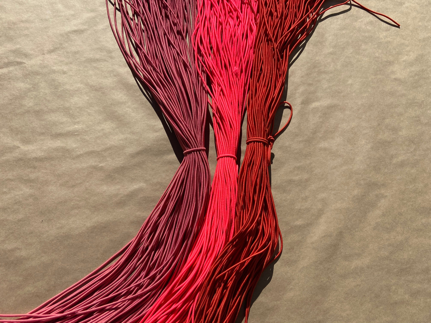 flat shot of our mask color cords in dusty rose, fluoro pink, and brick