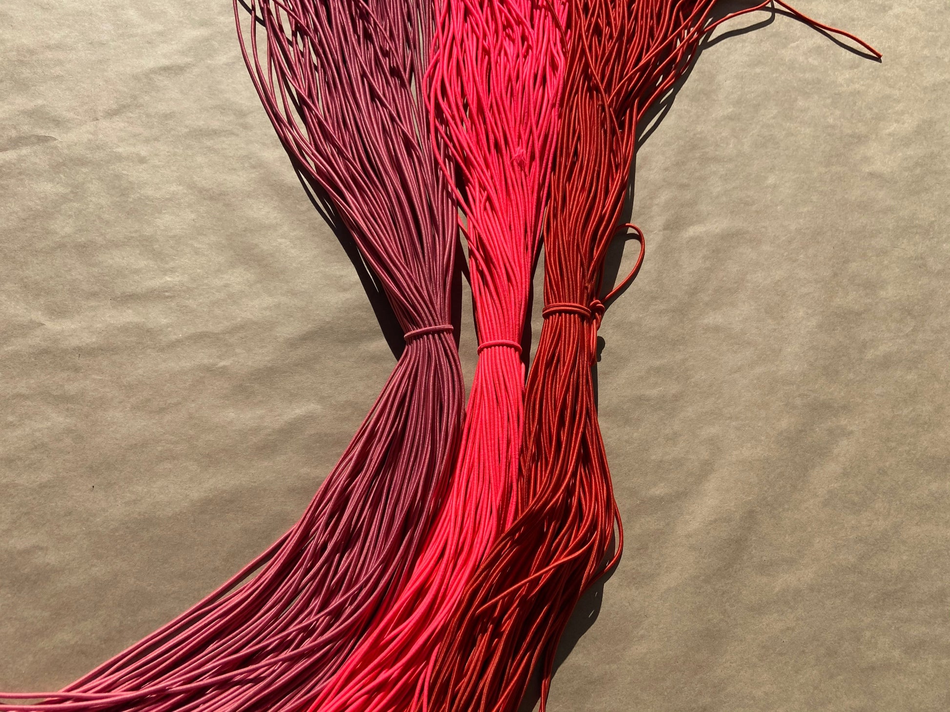 flat shot of our mask color cords in dusty rose, fluoro pink, and brick