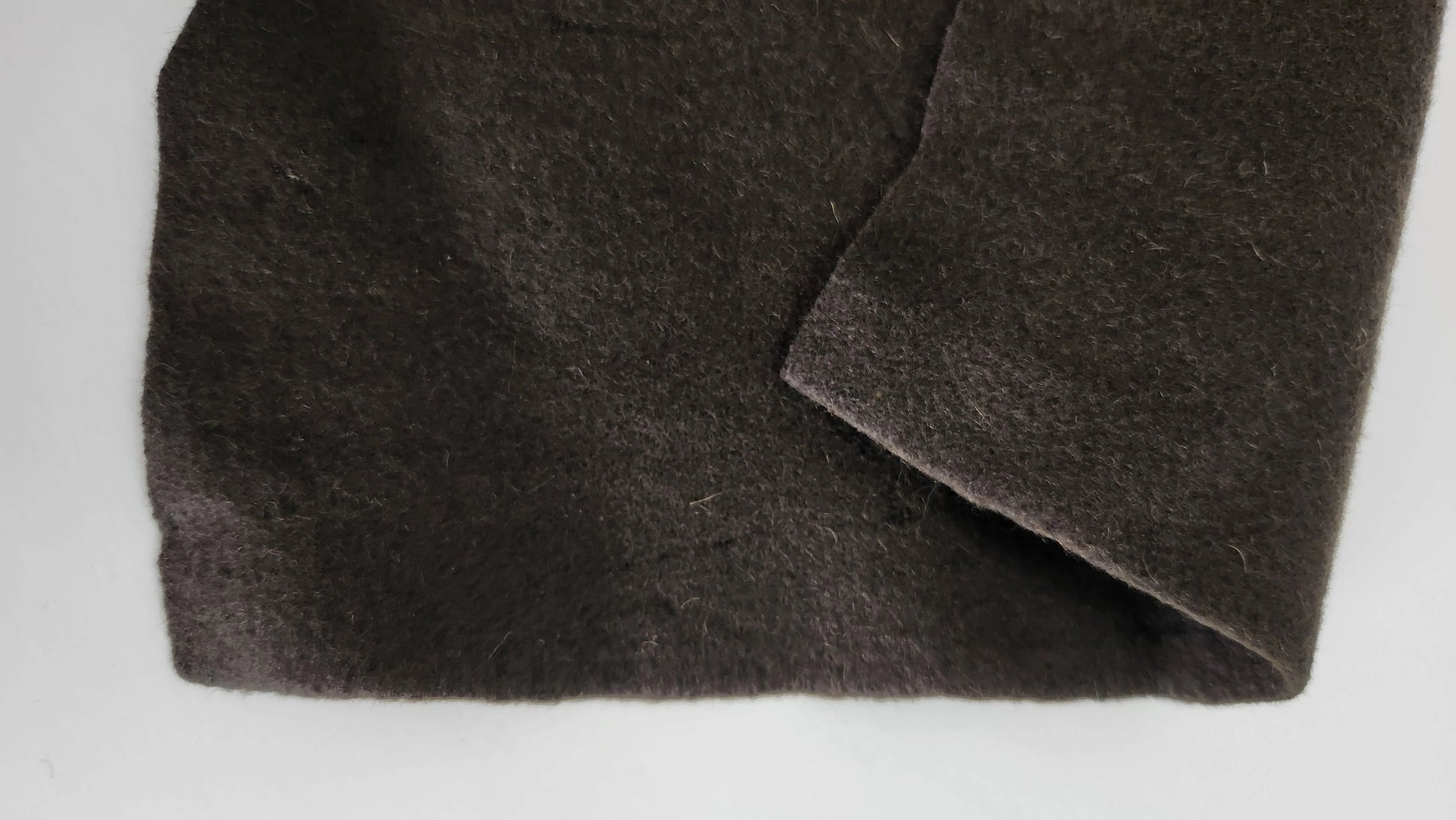 Close-up of dark olive wool felt fabric with a plain background